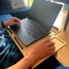 Osoba pracująca na laptopie Lenovo Legion przy użyciu podstawki LapPad, siedząc na kanapie.