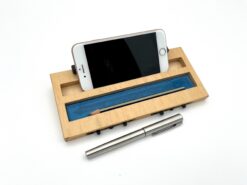 Moduł smartfon LapPad w naturalnym kolorze z niebieskim akcentem, umieszczony na białym tle. Moduł prezentuje przestrzeń na telefon, ołówek i długopis, a w tle widoczna metalowa pióro.
