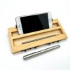 Moduł smartfon LapPad w kolorze naturalnym z telefonem zamocowanym w dedykowanej przestrzeni, obok ołówka, listewki pomocniczej i metalowego długopisu, na białym tle.