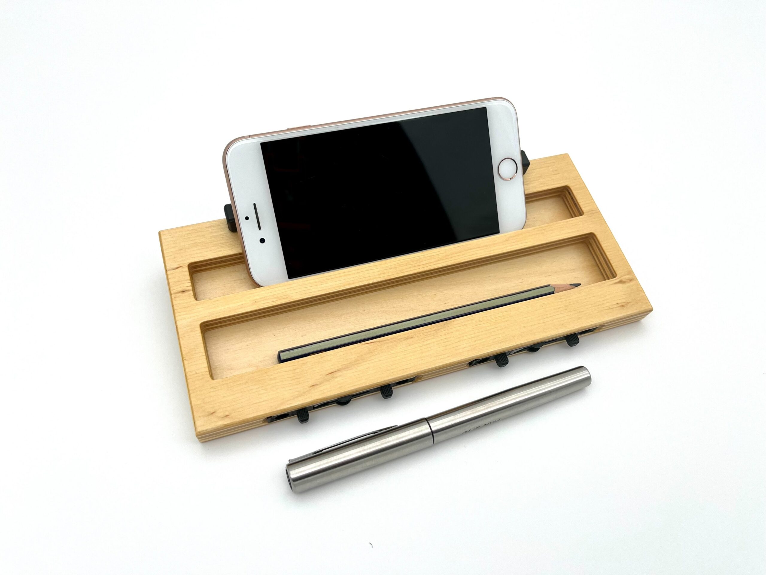 Moduł smartfon LapPad w kolorze naturalnym z telefonem zamocowanym w dedykowanej przestrzeni, obok ołówka, listewki pomocniczej i metalowego długopisu, na białym tle.