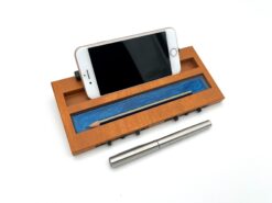 Moduł smartfon LapPad w kolorze Oregon z uchwytem na smartfon, detalami epoksydowymi w kolorze niebieskim oraz miejscem na ołówek, obok metalowego długopisu, na białym tle.