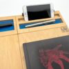 Naturalny moduł przybornik LapPad z niebieskimi detalami epoksydowymi, zamontowany na podstawce LapPad, z miejscem na smartfon i akcesoria biurowe, na białym tle.