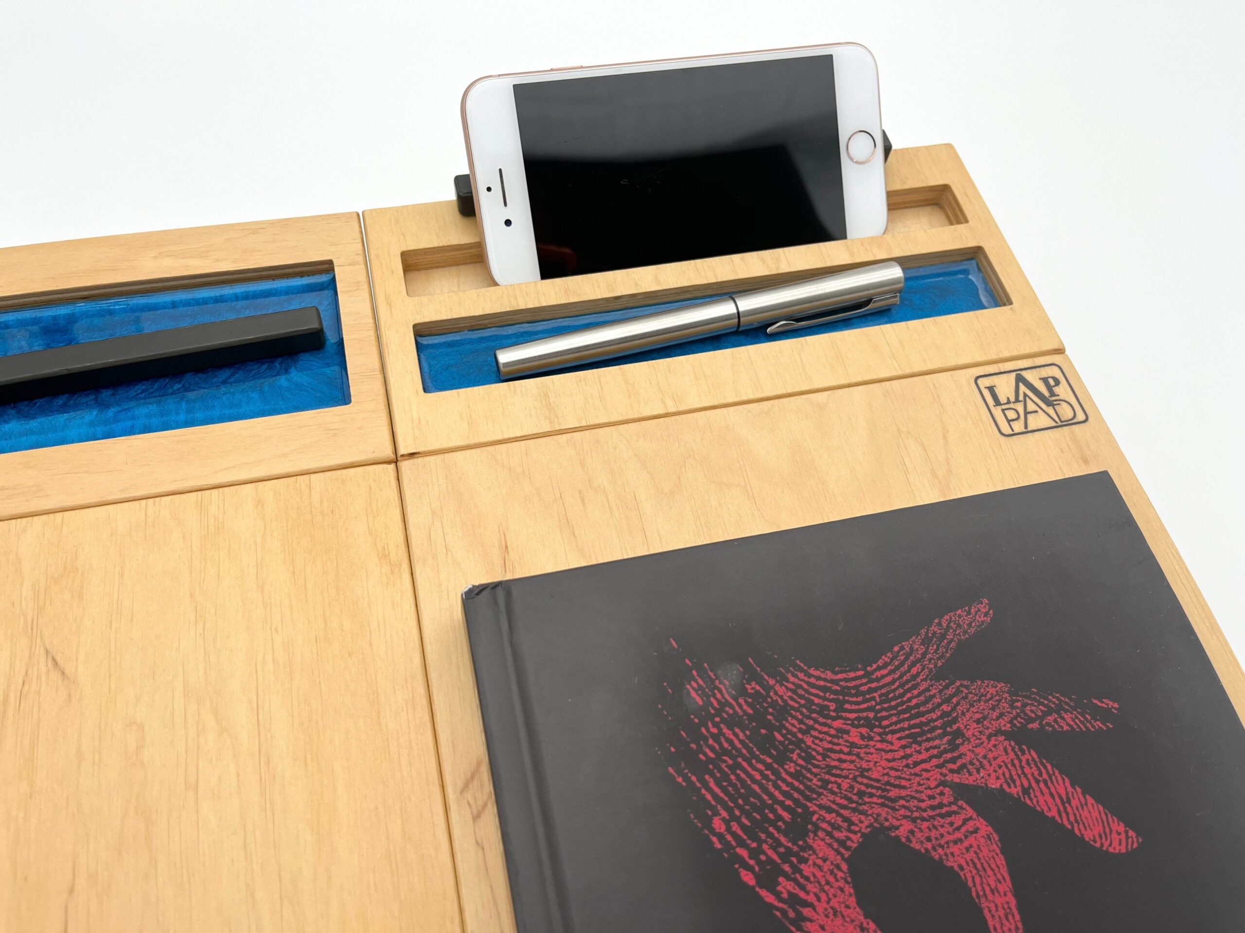 Naturalny moduł przybornik LapPad z niebieskimi detalami epoksydowymi, zamontowany na podstawce LapPad, z miejscem na smartfon i akcesoria biurowe, na białym tle.