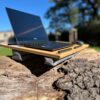 Laptop Asus na ergonomicznej podstawce LapPad z gąbkami pozycjonującymi, ustawiony na pniu drzewa w słonecznym otoczeniu.