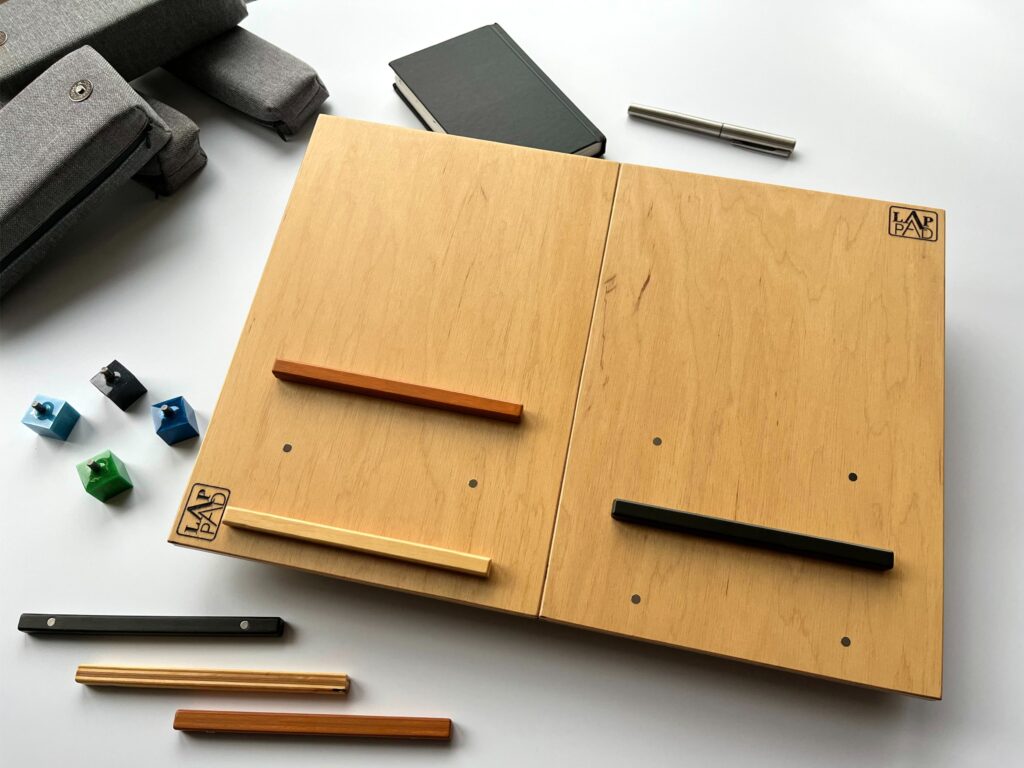 LapPad – ergonomiczna podstawka pod laptopa w naturalnym kolorze sklejki z pomarańczową, czarną i złotą listewką oraz kolorowymi kluczykami montażowymi