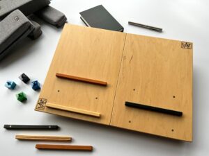 LapPad – ergonomiczna podstawka pod laptopa w naturalnym kolorze sklejki z pomarańczową, czarną i złotą listewką oraz kolorowymi kluczykami montażowymi