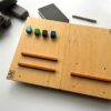 LapPad – ergonomiczna podstawka pod laptopa w naturalnym kolorze sklejki z pomarańczowymi listewkami i kolorowymi kluczykami montażowymi.