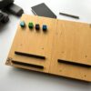 LapPad – ergonomiczna podstawka pod laptopa w naturalnym kolorze sklejki z czarnymi listewkami i kolorowymi kluczykami montażowymi.