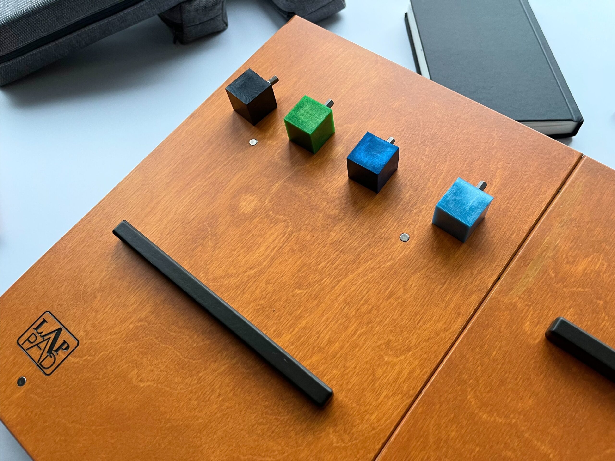 LapPad – ergonomiczna podstawka pod laptopa w kolorze Oregon z czarnymi listewkami pomocniczymi i kolorowymi kluczykami montażowymi.