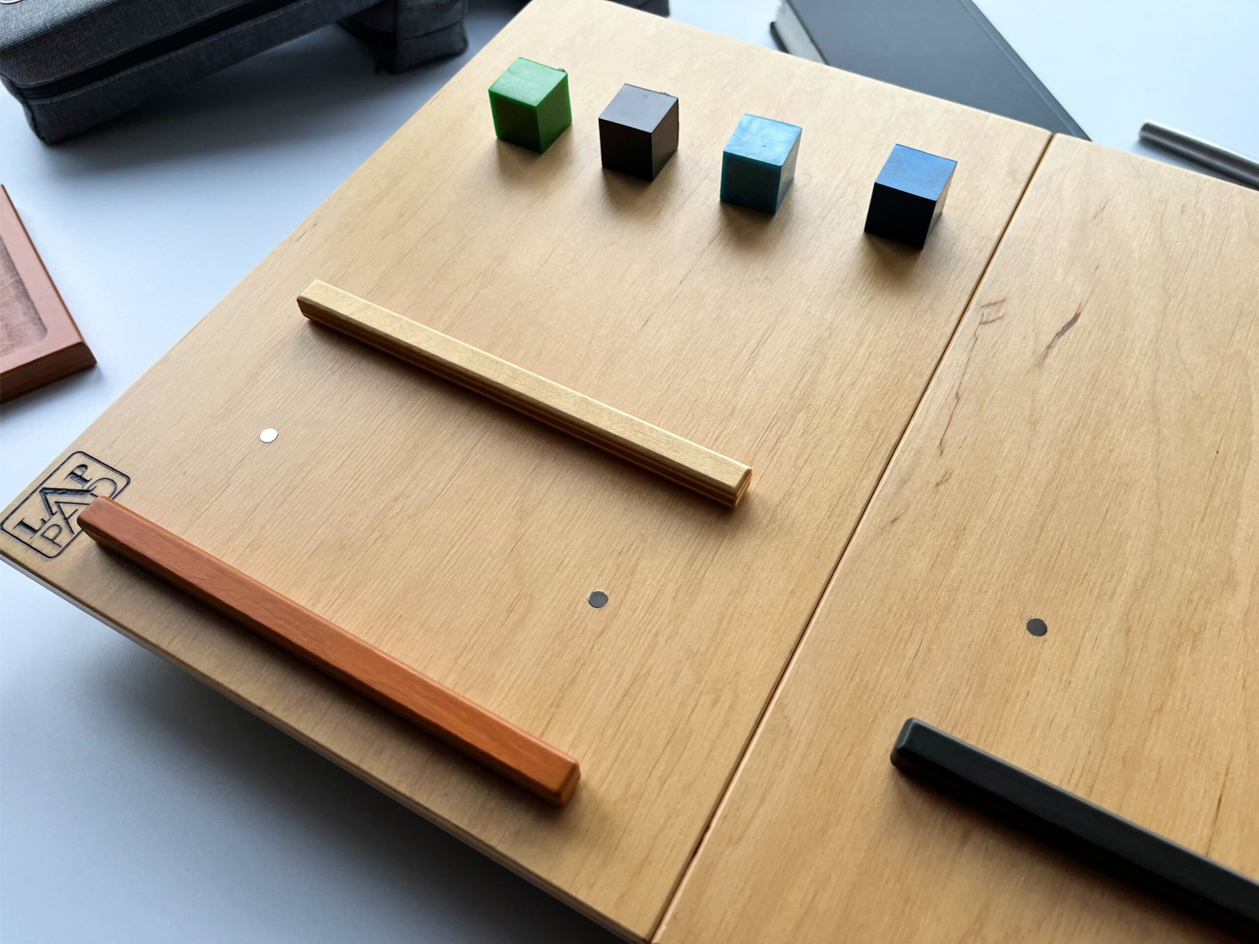 Ergonomiczna podstawka pod laptopa LapPad – kolorowe listewki pomocnicze i kluczyki montażowe na powierzchni ze sklejki.
