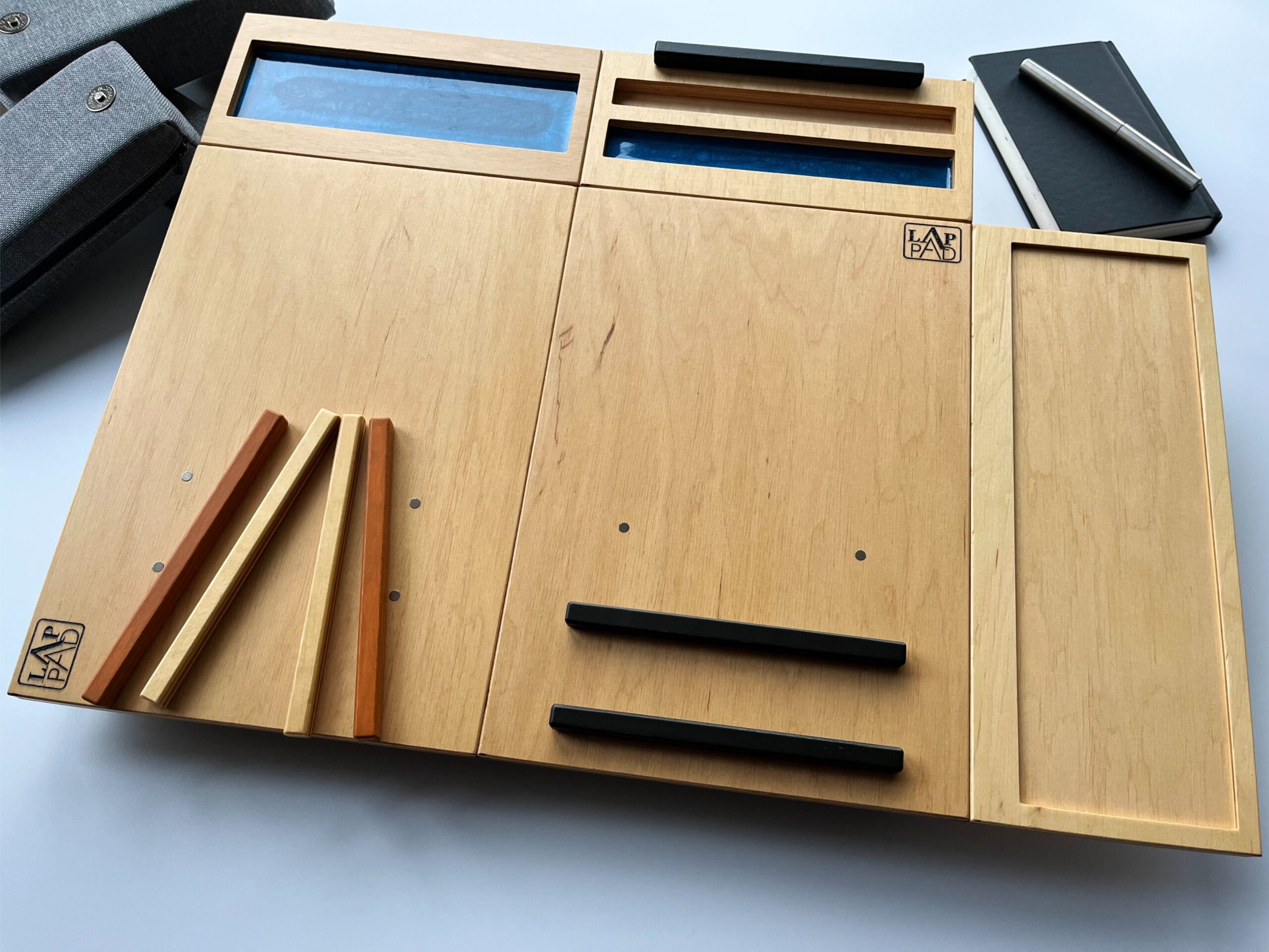 Ergonomiczna podstawka pod laptopa LapPad – listewki pomocnicze w naturalnym kolorze sklejki, czarne moduły i ozdobne wykończenie z żywicy epoksydowej.