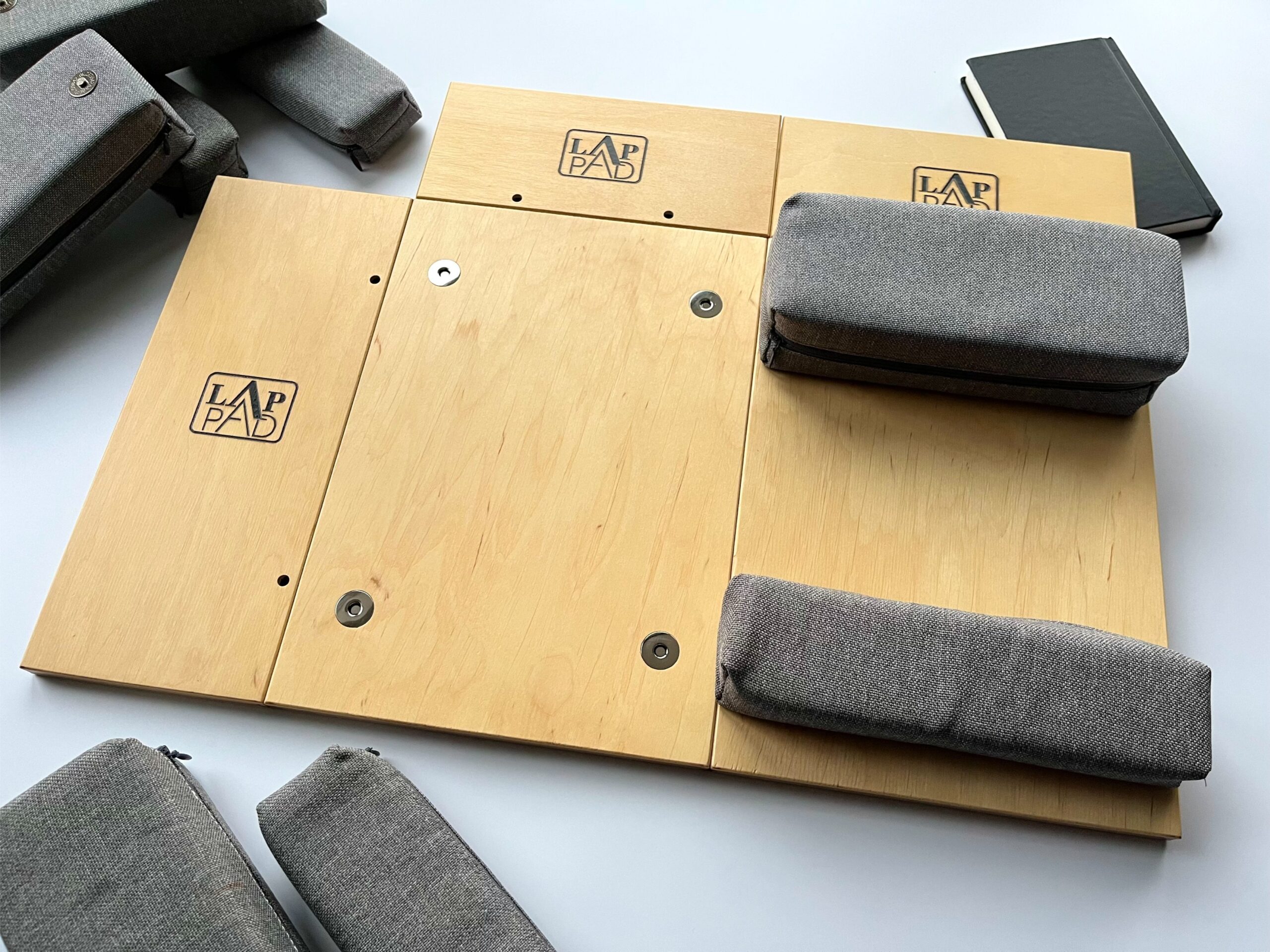 Ergonomiczna podstawka pod laptopa LapPad – elementy ze sklejki z logo i szare gąbki pozycjonujące dla poprawy stabilności i komfortu pracy.